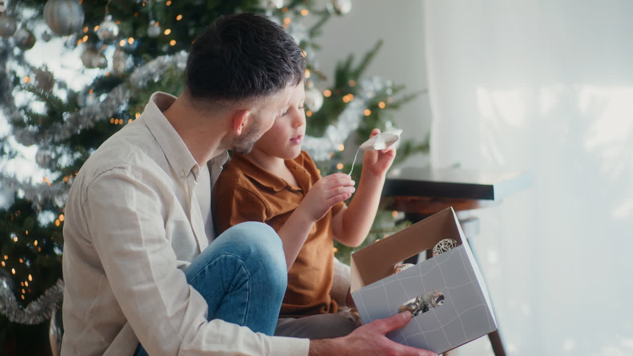 어린 소년과 아빠는 크리스마스 장식을 준비합니다.