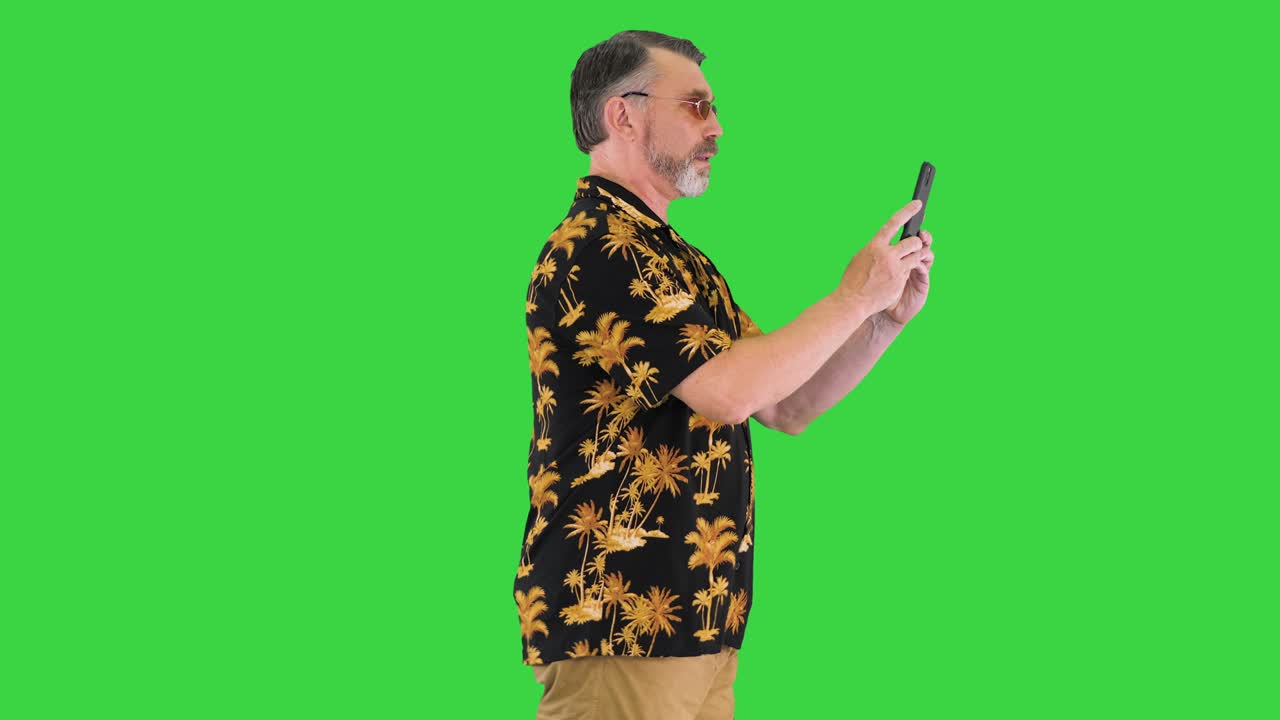 Turista idoso tirando foto com a câmera do celular enquanto caminha em uma Tela Verde, Chroma Key