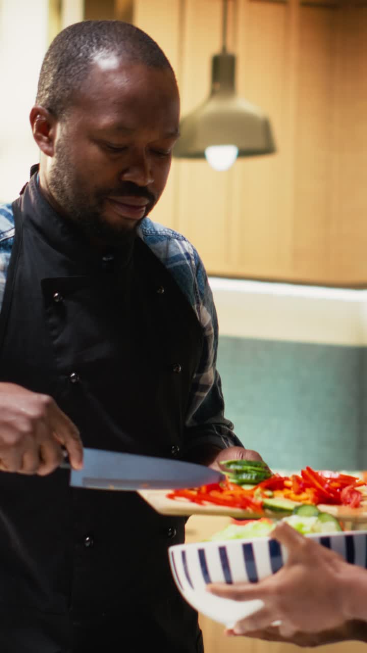 Vertical Video African american people adding chopped veggies in a bowl for fresh salad