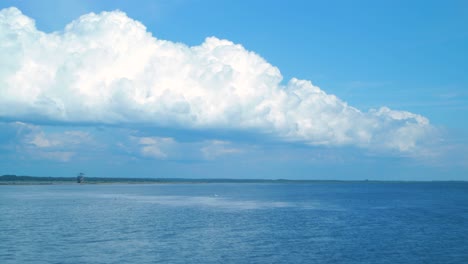 time lapse of beautiful white fast moving puffy cumulus clouds at footbridge path and birdwatching tower at lake liepaja in sunny summer day, wide shot