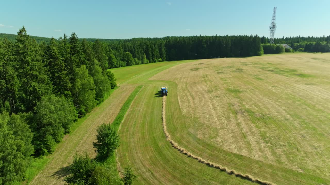 Drone view of a tractor making hay bales. Hot summer in the countryside. Working in a meadow. Czech Republic