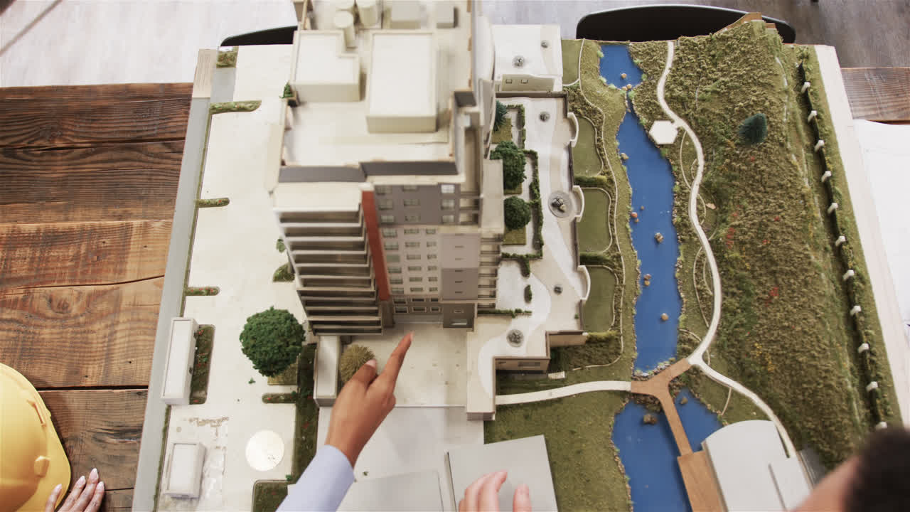 manos de diversos arquitectos masculinos y femeninos discutiendo el modelo arquitectónico de la construcción, cámara lenta