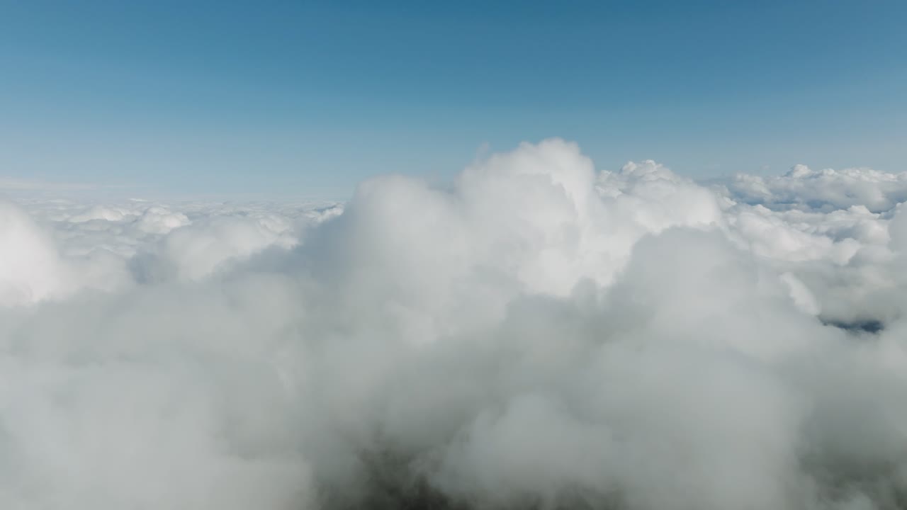 Aerial flyover revealing a ocean of white clouds stretching endlessly under clear blue skies