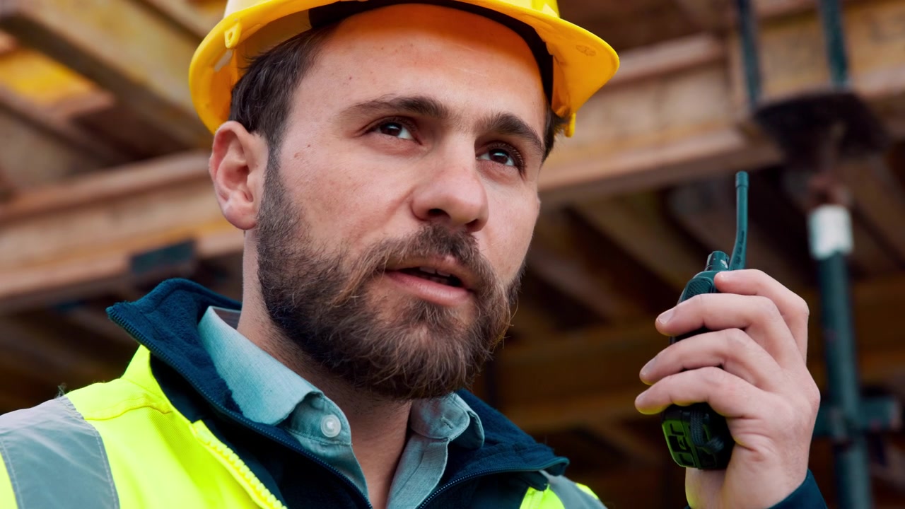 Construction Foreman Communicating via Two-Way Radio on Building Site