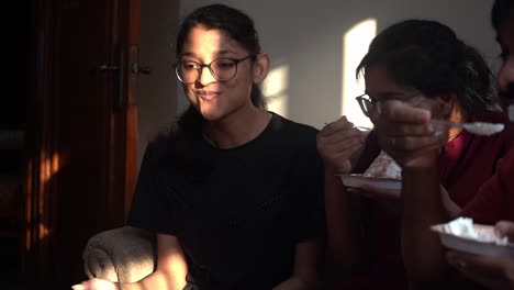 teenage girls eating cake inside the house in agra, india - medium shot