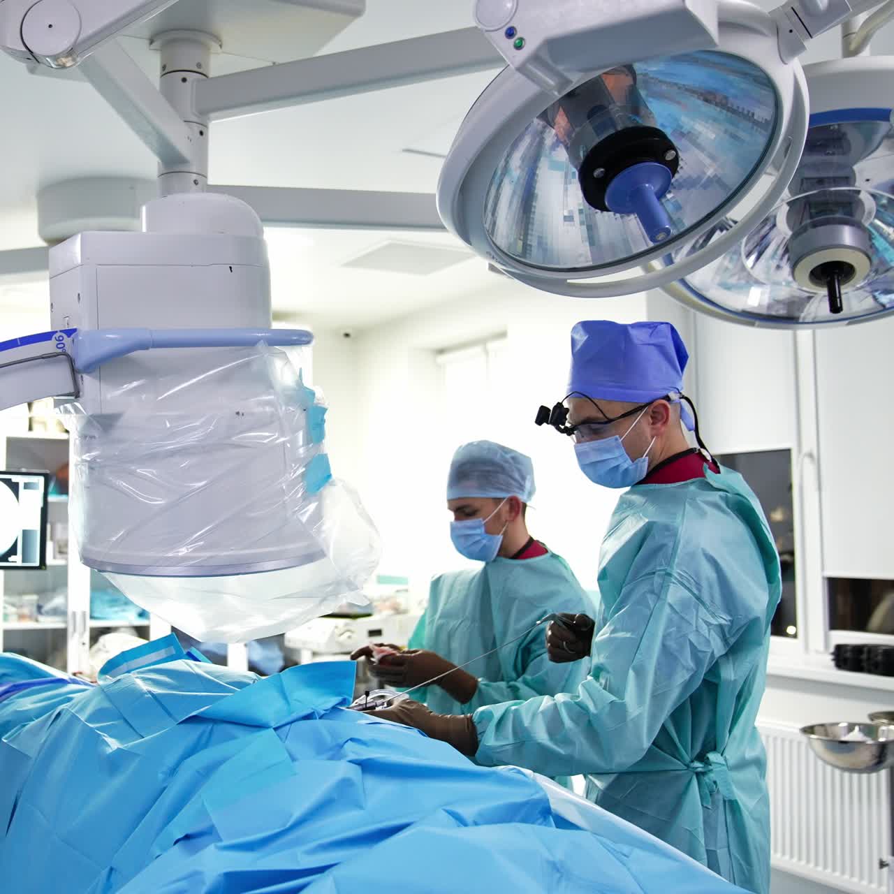 Two surgeons carry out the operation and look at the screen. Well-equipped surgery room in modern hospital