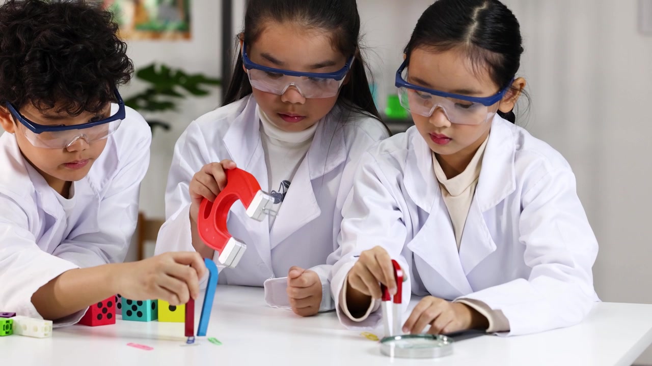 Siswa sekolah dasar mengenakan kacamata pengaman menjelajahi magnetisme menggunakan magnet tapal kuda selama pelajaran sains di kelas.