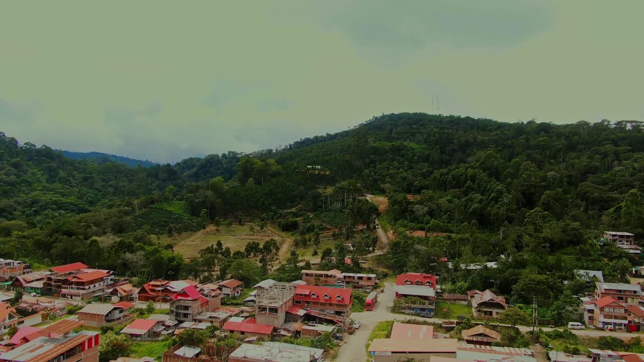 Drone mengitari kota Villa Rica, Peru, yang terletak di dalam hutan dataran tinggi Chanchamayo, menunjukkan vegetasi pegunungan hijau yang lebat di bawah langit berawan