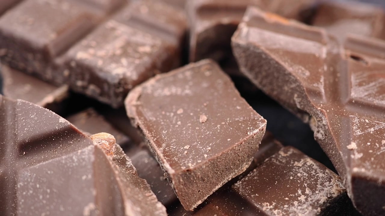 Primo piano di pezzi di cioccolato fondente spezzati su una superficie scura