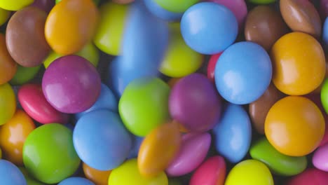 movimiento lento de primer plano de caramelos de chocolate redondos de colores, dragee. rotación y caída de caramellos de chocolate multicolores