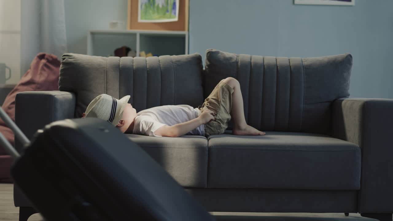 작은 소녀는 거짓말하는 형제와 함께 소파 주위에 수하물을 끌고