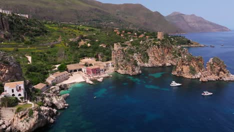 Impresionante-Vista-Aérea-De-La-Pintoresca-Casa-Rosa-En-La-Costa-Rocosa-Del-Mediterráneo-En-Sicilia,-Italia