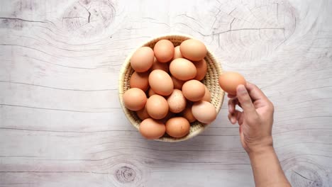 hand picking an egg from a basket of eggs