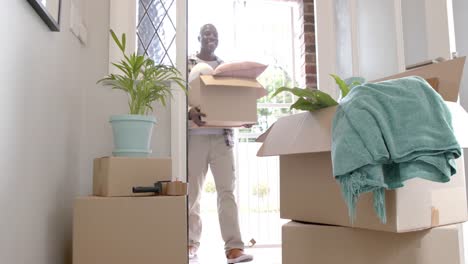 Happy-african-american-man-carrying-boxes-at-home,-slow-motion