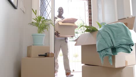 happy african american man carrying boxes at home, slow motion