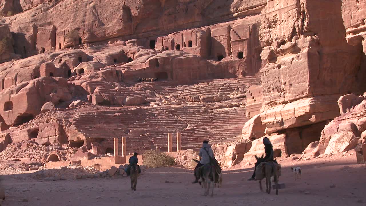 la gente monta burros cerca del antiguo anfiteatro en las antiguas ruinas nabateas de petra jordania