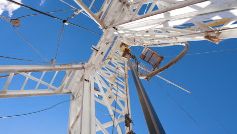 rotating pole is attached to the white metal tower. low angle view on the drilling equipment working outdoors.