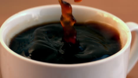 sugar cube falling into cup of coffee