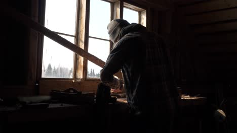 person is working on old and dusty wood workbench against window light