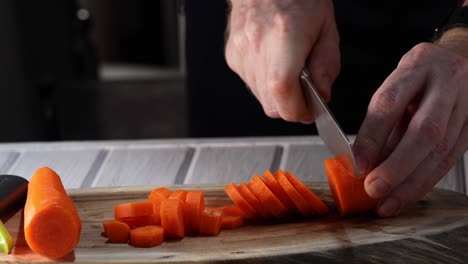 a man slices a carrot into slices on a wooden background. 4k video