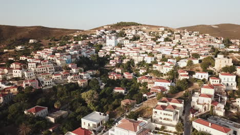 greece, ionusses island, drone footage of the town spread to the hills of the island, footage starts from the bottom and moves towards to the hills and slightly turns around.