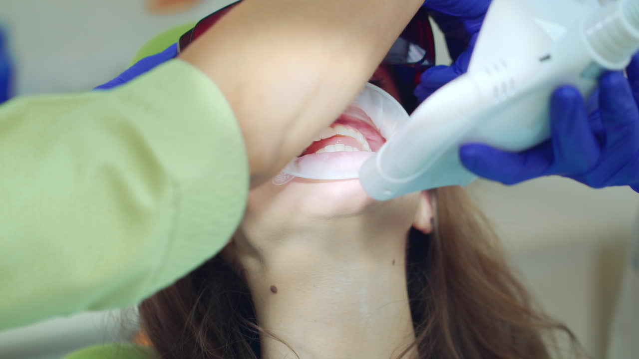 Diş kliniğinde diş beyazlatma prosedüründeki hasta. Doktor ışığı açıyor.