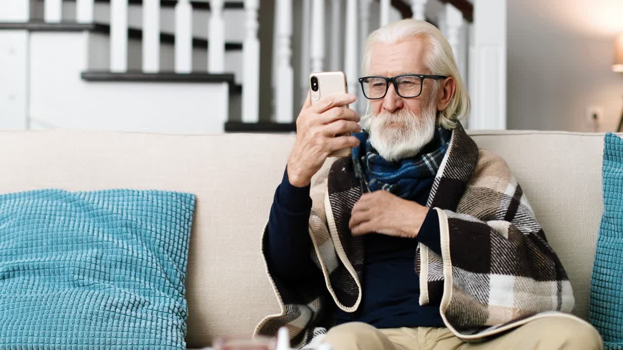 retrato de un hombre enfermo sentado en una habitación acogedora y chateando por video en el teléfono celular