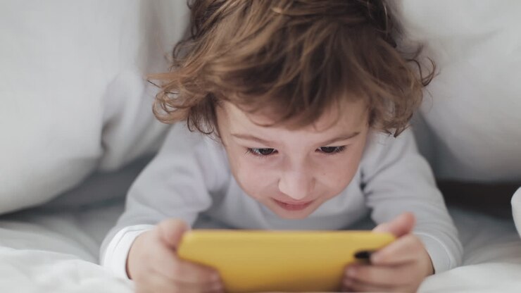 Child using phone in bed