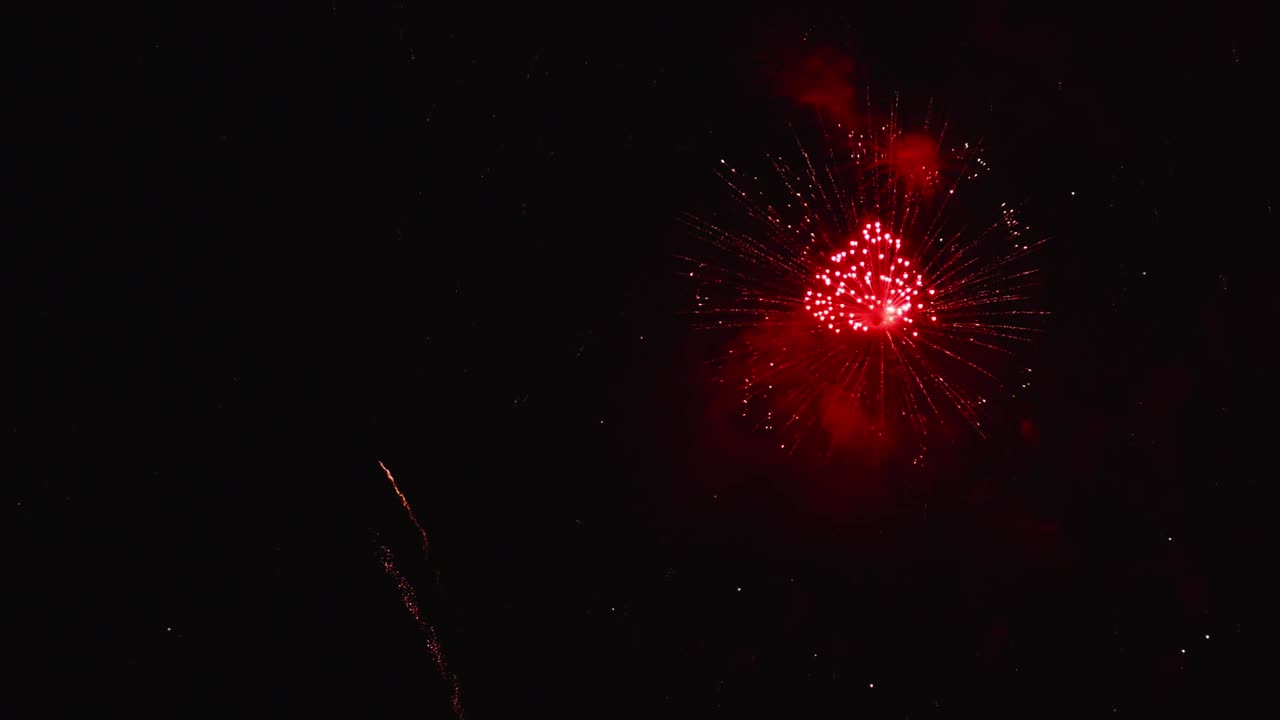 Fuochi d'artificio reali che esplodono in un frame celebrativo con loop continuo, luci bokeh sfocate astratte nel cielo notturno durante un festival pirotecnico luminoso.