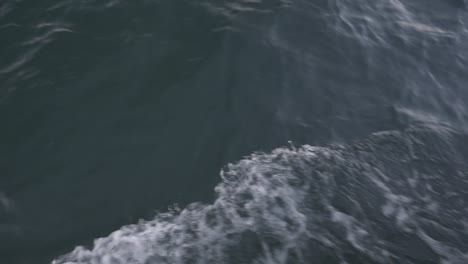 waves from a boat moving in the ocean, camera onboard handheld, camera tilt up