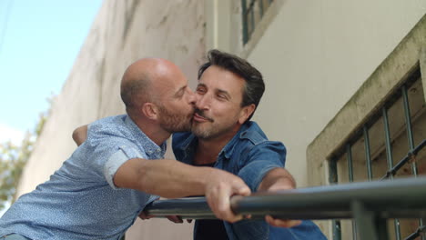 happy gays kissing and holding on to railing of stairs