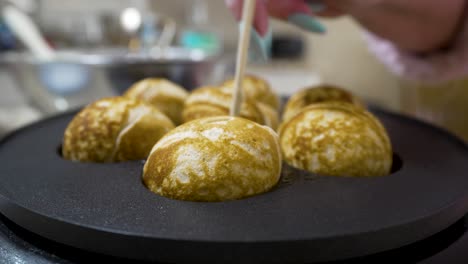 turning aebleskivers in the pan to cook them evenly in the rounded pockets - aebleskiver series