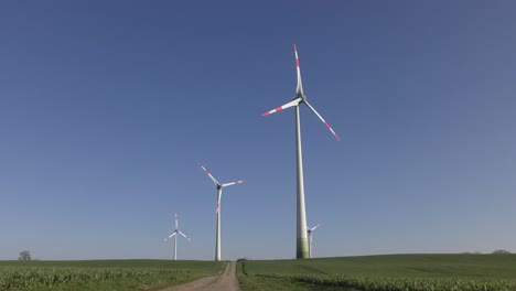 wind turbine stands on a green field in front of a cloudless blue sky