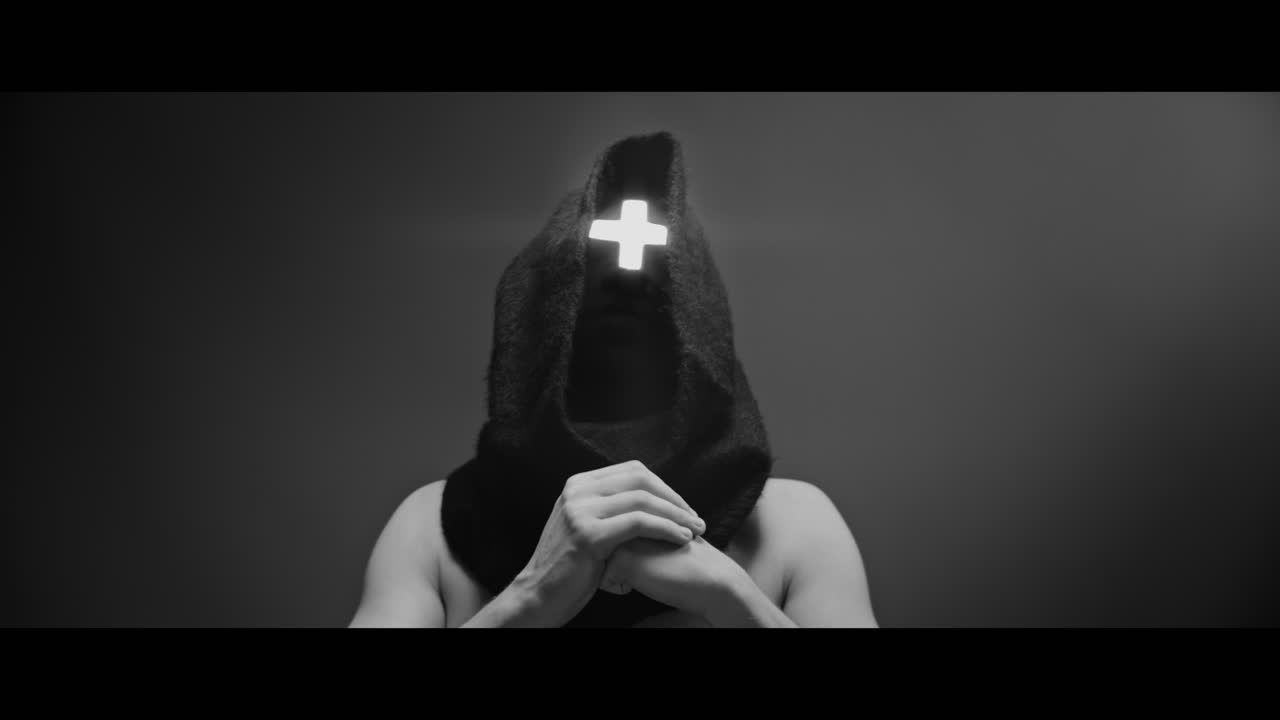 Masked man with cross of light glowing on his face prays