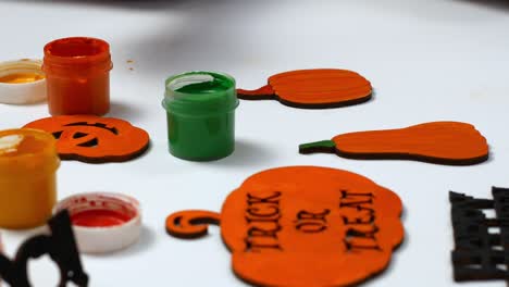 children make their own halloween decor. children paint a pumpkin orange with the inscription trick or treat