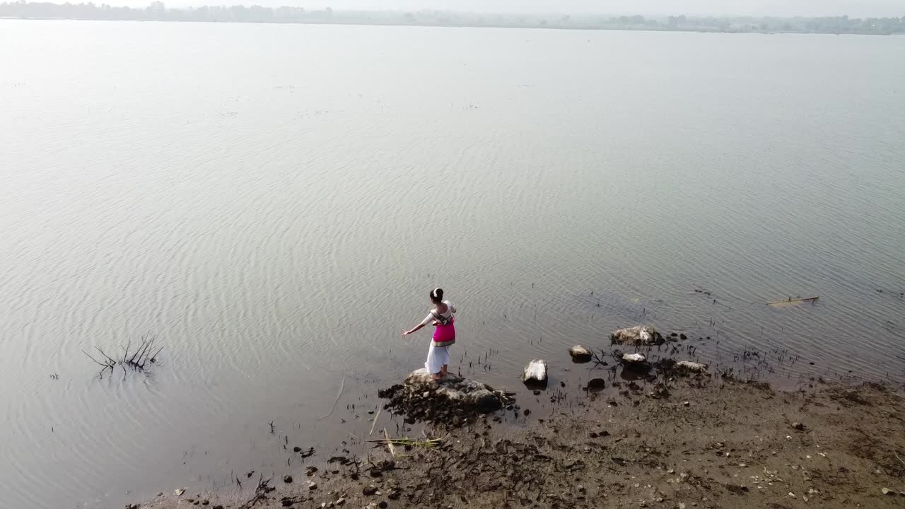 una bailarina de bharatnatyam que muestra una pose clásica de bharatnatyam en la naturaleza del lago vadatalav, pavagadh