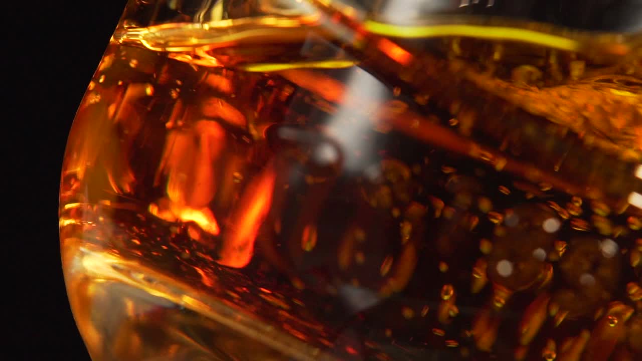 Close up at the bottom of a glass where pure whisky is being served