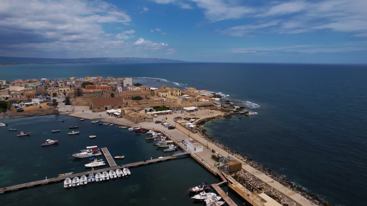Aerial footage of Marzamemi, Sicily, Italy. Coastline with historic port, narrow streets, clear blue water