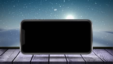 animation of blank smartphone screen with winter scenery and snow falling on wooden surface