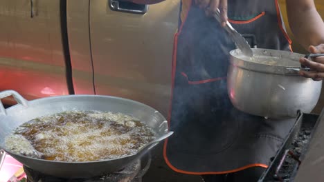 asian lady deep frying chicken on the street side at dirty street food restaurant processing in thailand