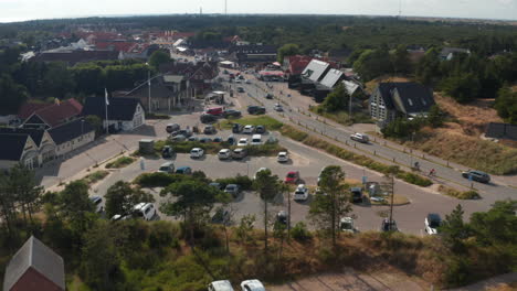 Fly-above-cemetery-and-car-park.-Aerial-with-of-traffic-on-road-in-small-town.-Flat-coastal-landscape-around.-Denmark