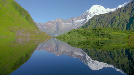 landscape-of-Annapurna-mountain-reflected-in-lake-surrounded-by-green-Nepal,-Clear-weather-drone-shot-4K