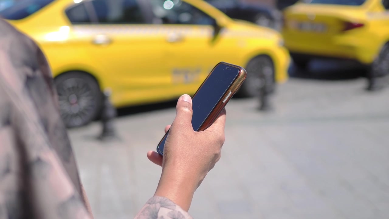 Orang Memegang Smartphone di Jalan Kota dengan Taksi Kuning