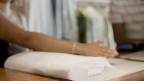 Closeup-of-shop-assistant-packing-purchase-on-desk-counter.