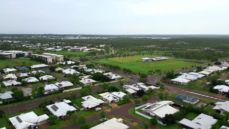 Aerial-drone-of-Residential-Surburb-On-A-Rainy-Day-with-Uniform-White-Roofed-Homes-by-Community-Sports-Field