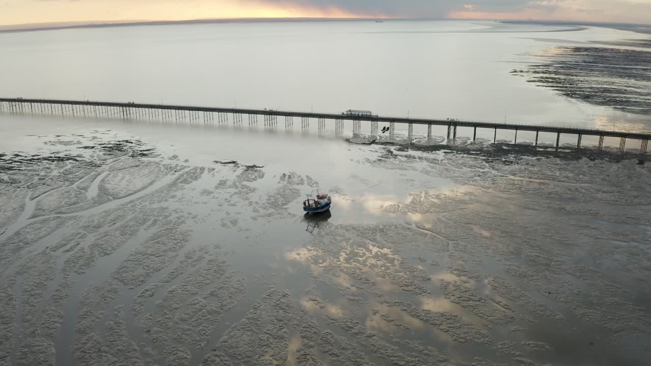 고독한 보트와 반사가 황금색을 칭찬하는 사우스엔드의 템스 어귀에 일몰