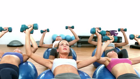 fitness class lifting hand wieights on exercise balls