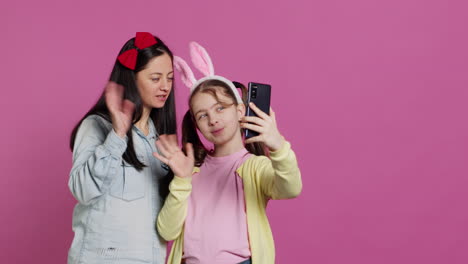 little schoolgirl and her mom talking on videocall meeting in studio