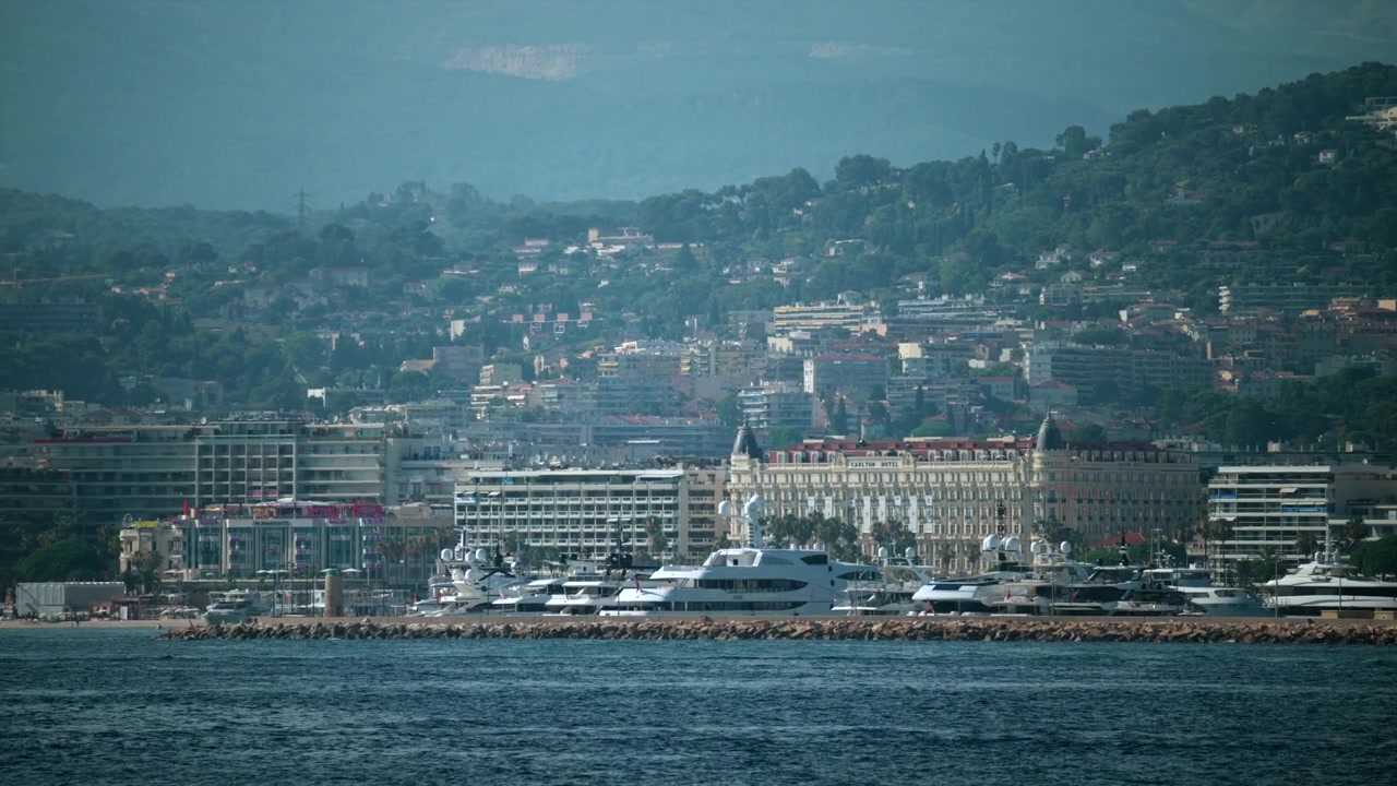 Panorama urbano di Cannes lungo la Costa Azzurra, che mostra yacht di lusso in porto con l'iconico hotel Carlton e gli edifici sulle colline, Cannes, Francia.