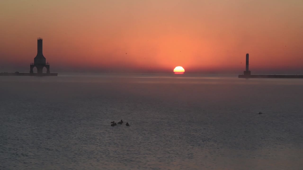 un hermoso amanecer en el lago michigan con un faro y un rompeolas